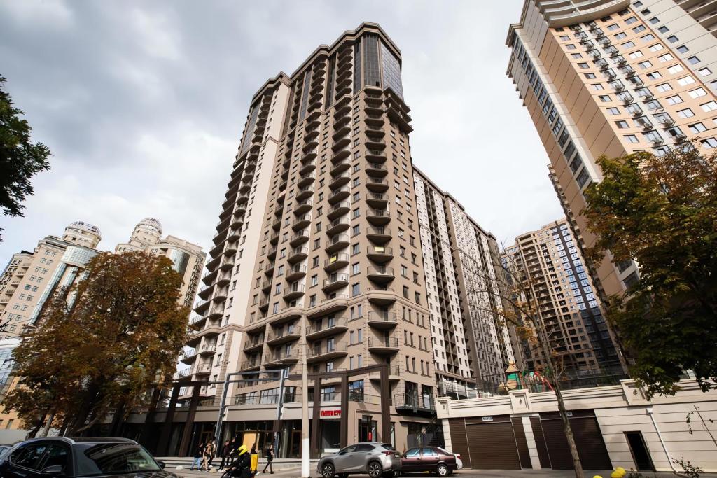 a tall building with cars parked in front of it at Rodos ArCadia Apartments in Odesa