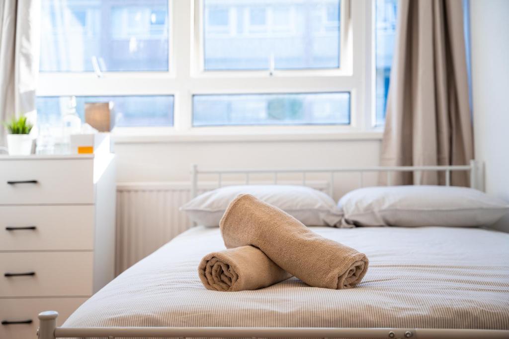 a towel sitting on top of a bed with a window at Private Rooms near Canary Wharf in London