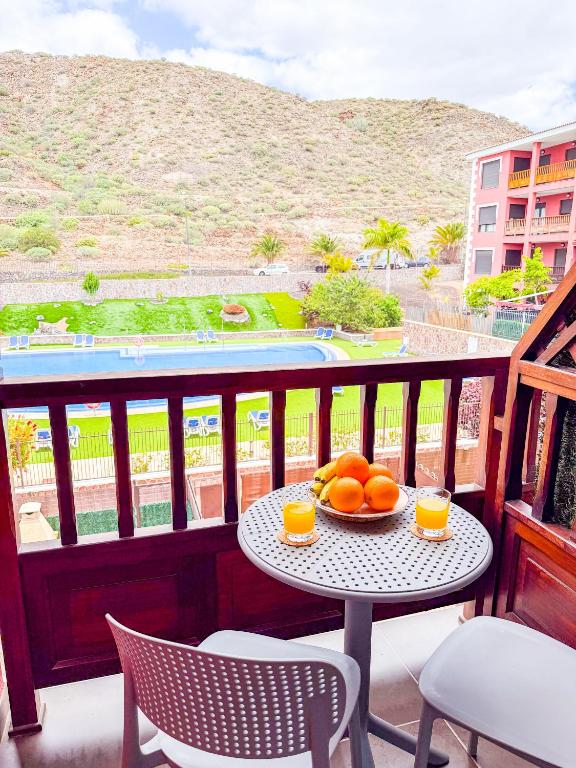 a table and chairs on a balcony with a bowl of oranges at Little Palmar with Free Parking & Pool & Padel in Palm-Mar