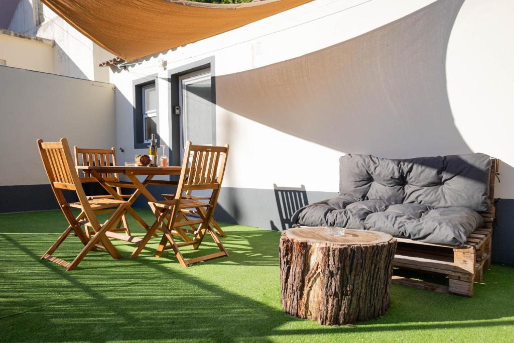 a patio with a table and chairs and a tree stump at Azorean Stays T1 in Lomba da Cruz