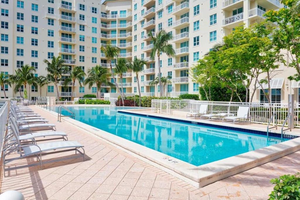 a swimming pool with lounge chairs and a large building at Modern Bedroom In Great Condo! Beach Pass Incl! in Boynton Beach