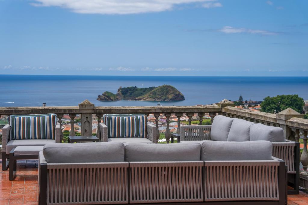 a couch sitting on a balcony with a view of the ocean at Vila Islet View in Vila Franca do Campo