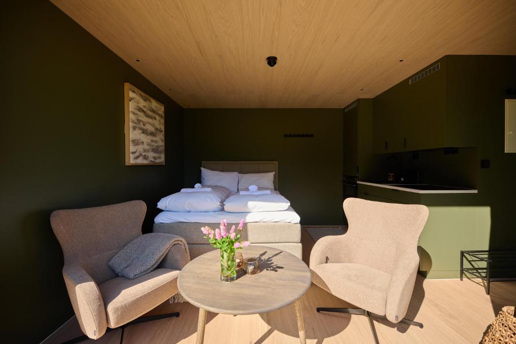 a bedroom with a bed and two chairs and a table at Hytte Blåtind, Rekkedal Gjestegard - Sæbø in Sæbø