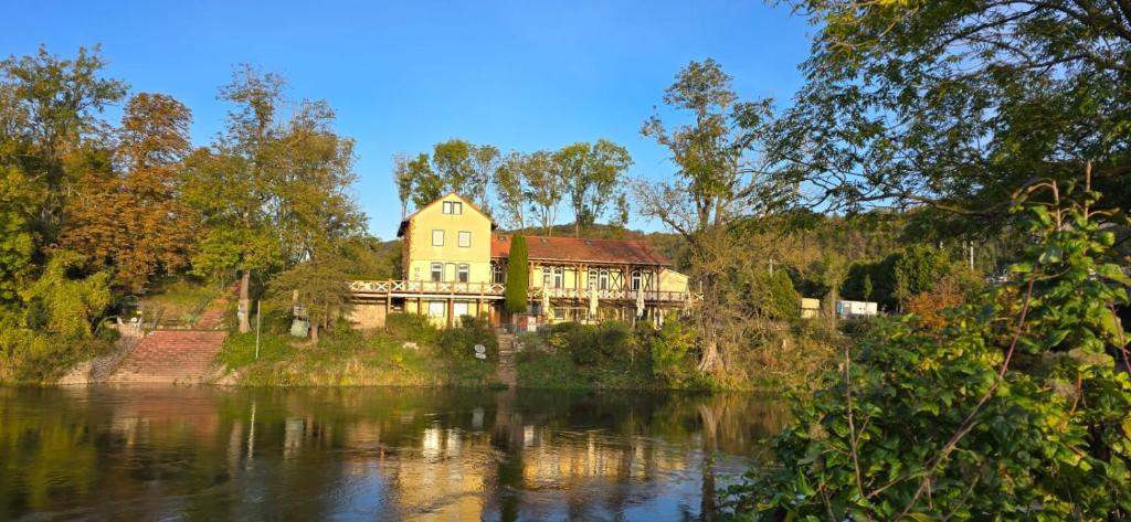 a large house sitting on the side of a river at Altes Saale Fährhaus in Naumburg