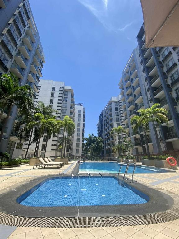 ein großer Swimmingpool mit Palmen und Gebäuden in der Unterkunft Bekipay Suite at One Palm Tree right across NAIA 3 in Manila
