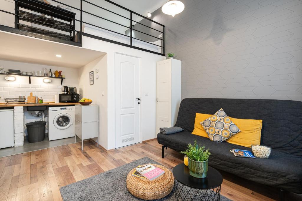 a living room with a black couch and a kitchen at Funhouse Dob in Budapest