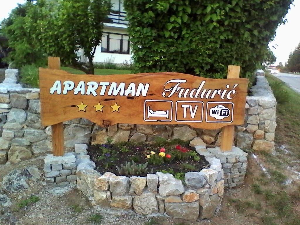 a sign for an apartment building in a rock wall at Apartment Fuduric in Slunj