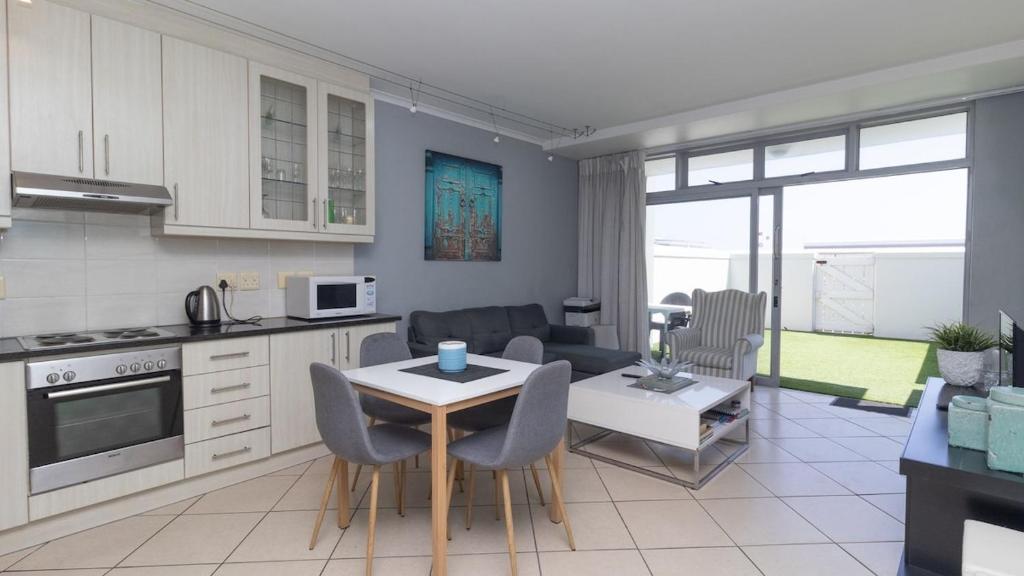 Una cocina y una sala de estar con mesa y sillas. en EasyCapeTown - Entire Flat in Big Bay, en Cape Town
