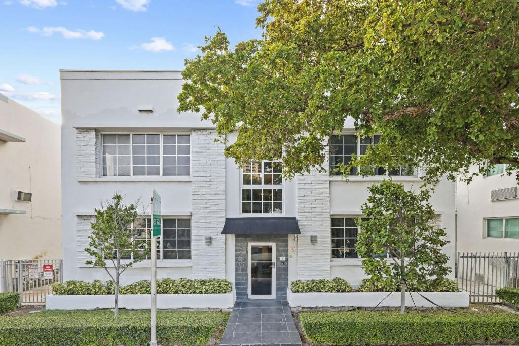a white house with a tree in front of it at Harding Apartments by Andes STR in Miami Beach