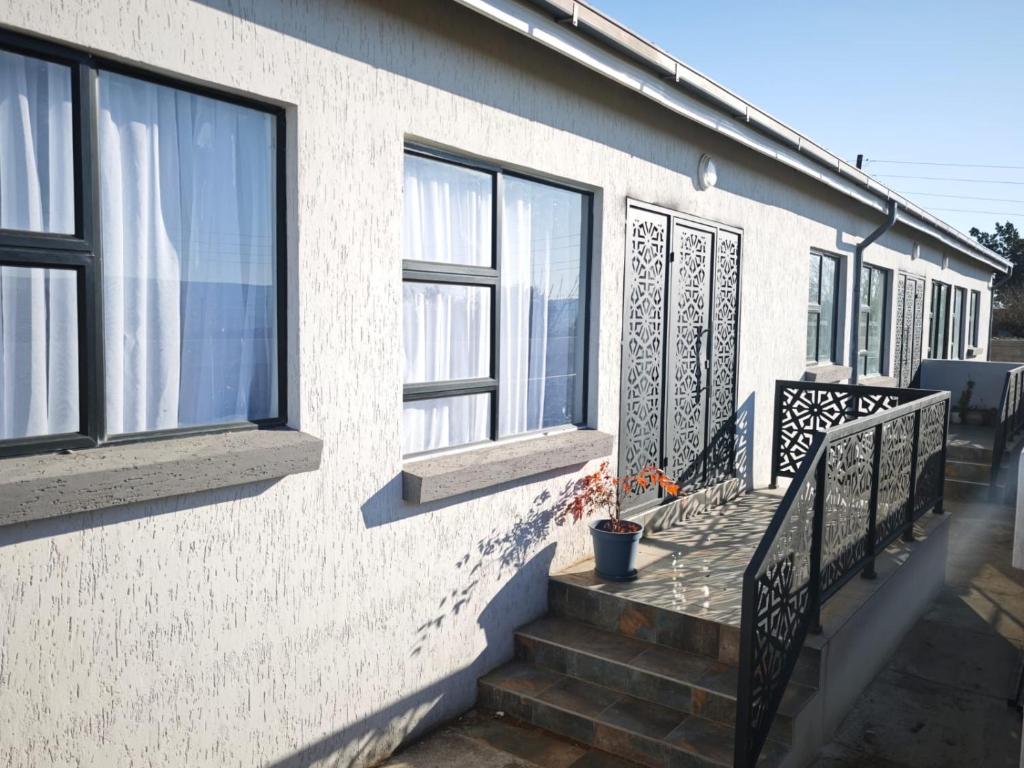 a house with a porch with windows and stairs at The Residence Apartments in Maseru