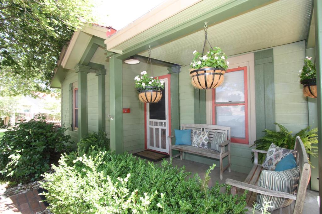 a porch of a house with two benches and flowers at Agape Front Cottage in Fredericksburg