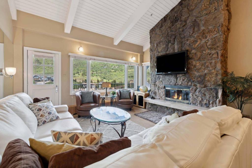 a living room with a stone wall with a fireplace at Lodge Tower 778 Two Bedroom Residence in Vail