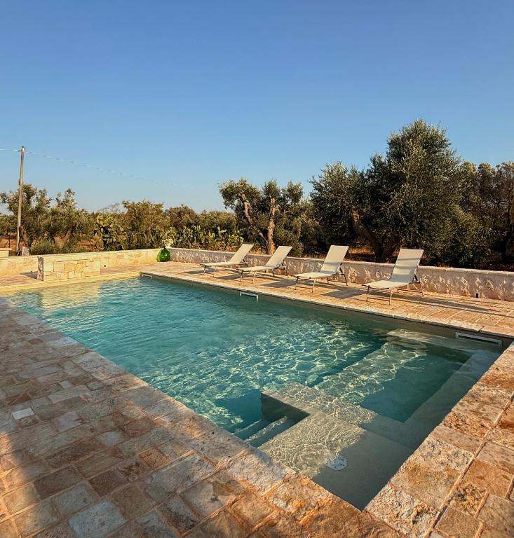 a swimming pool with lounge chairs and water at Trullo Tatauan in San Michele Salentino