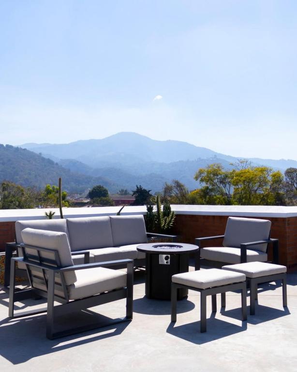a group of chairs and tables on a patio with mountains at Hotel El Descanso Cultural in Antigua Guatemala