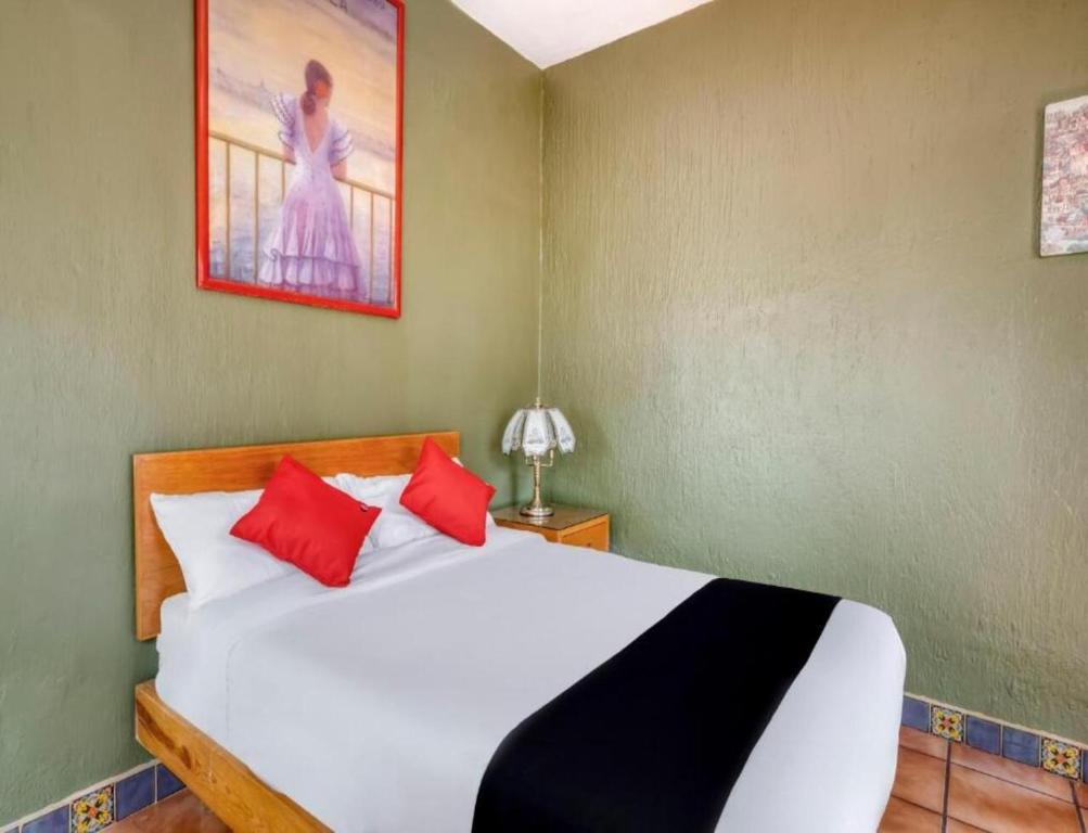a bedroom with a white bed with red pillows at Hotel Arana Tonalá in Guadalajara