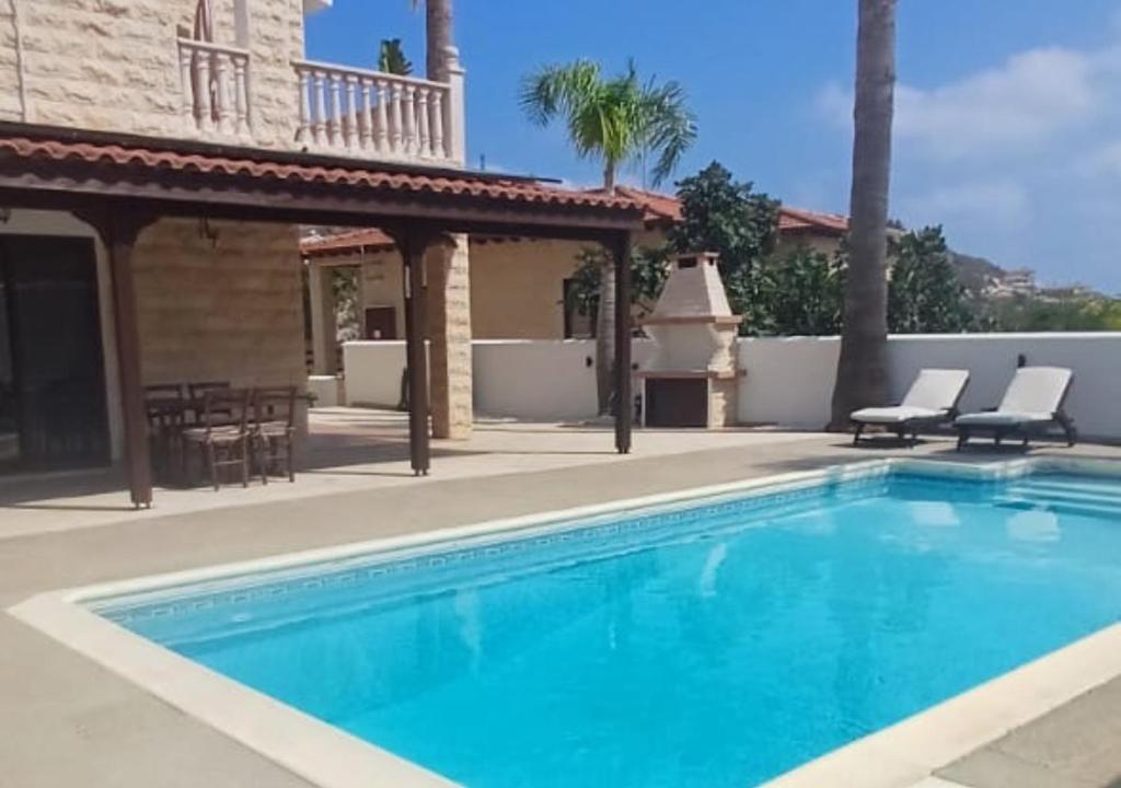 a swimming pool with two chairs and a house at Eros Villa-Private Luxury Estate in Pissouri