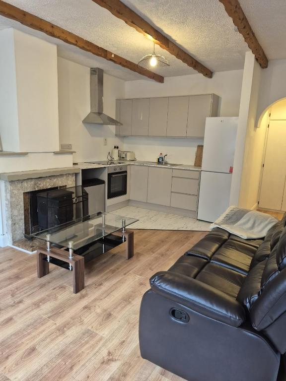 a living room with a black leather couch and a kitchen at Drumeenagh Lodge 