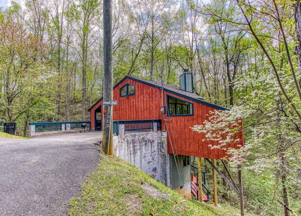 een rood huis op een heuvel in het bos bij Woods Child Cabin By Beyond Expectation W Hot Tub in Gatlinburg