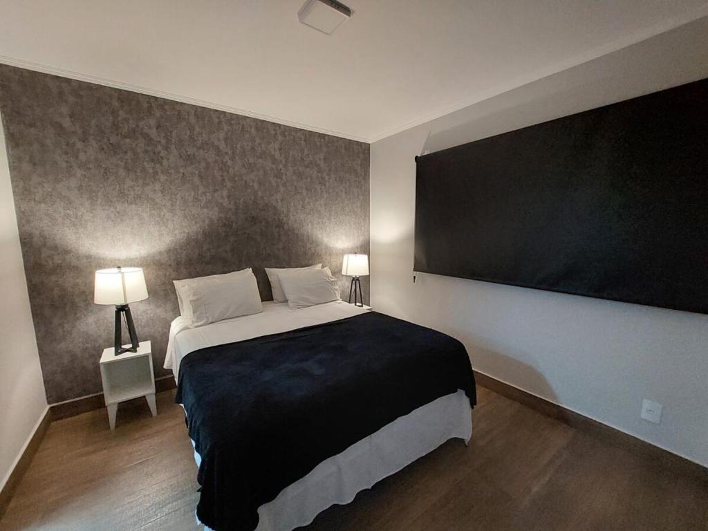 a bedroom with a large bed and a large flat screen tv at Apartamento Luxuoso decorado e mobiliado in Ribeirão Preto