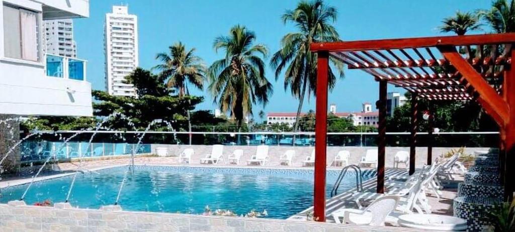 een zwembad met witte stoelen en palmbomen bij estudio de lujo 1709 in Cartagena