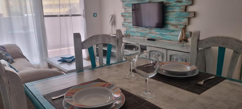 a dining room table with wine glasses and a television at La mariposa in Parque Holandes