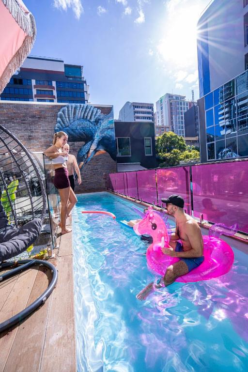 Un hombre y una mujer en una piscina con un jinete de unicornio rosa. en Brisbane Quarters, en Brisbane