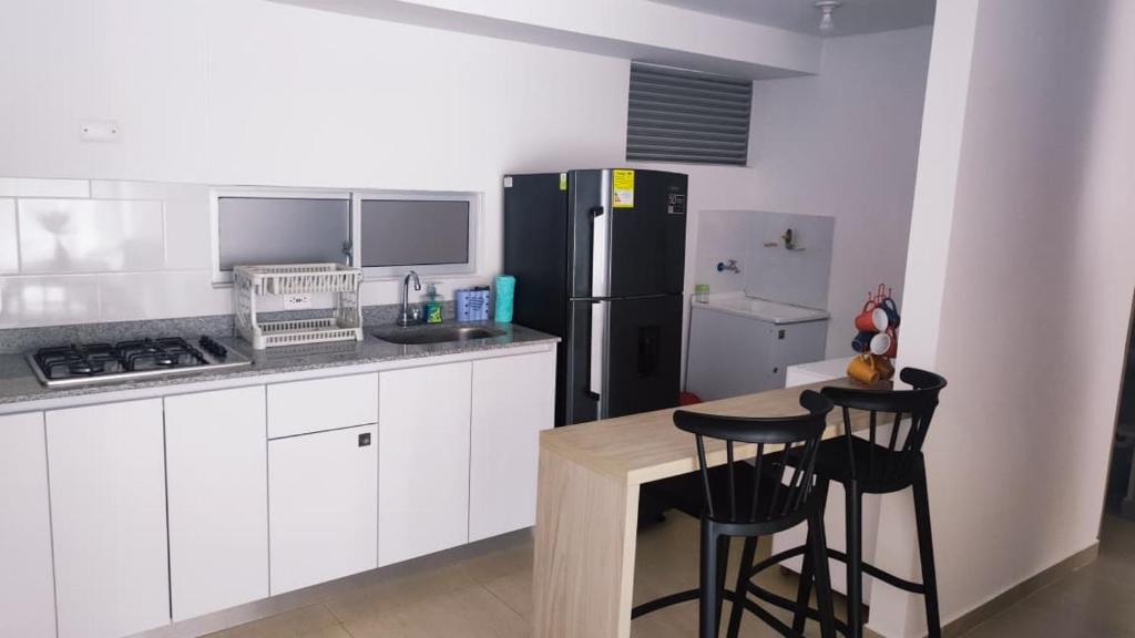 a kitchen with a refrigerator and two bar stools at Apartamento Vacacional Carmen de Apicala GursyHost in Carmen de Apicalá