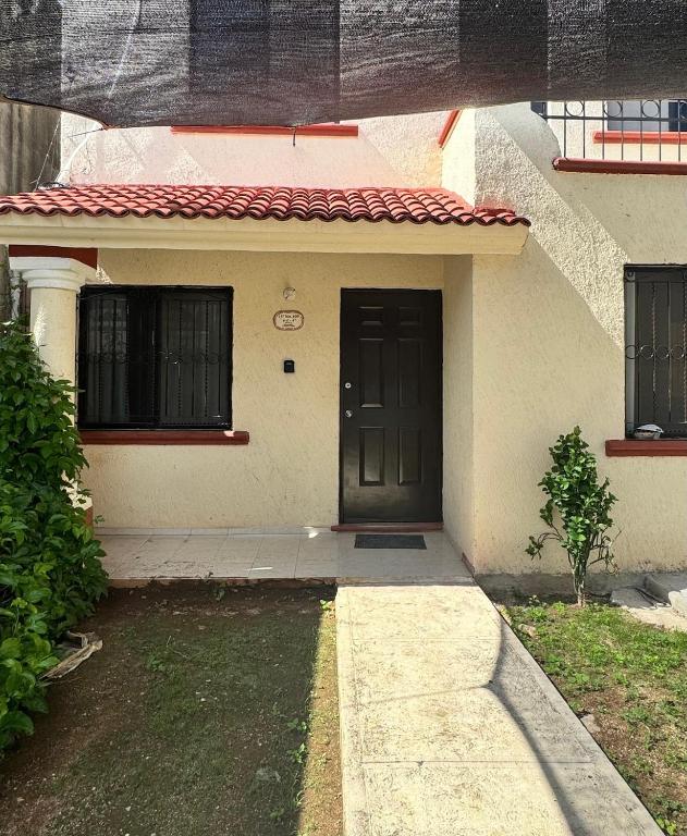 a house with a black door and a yard at Casa Amelia Victoria in Mérida