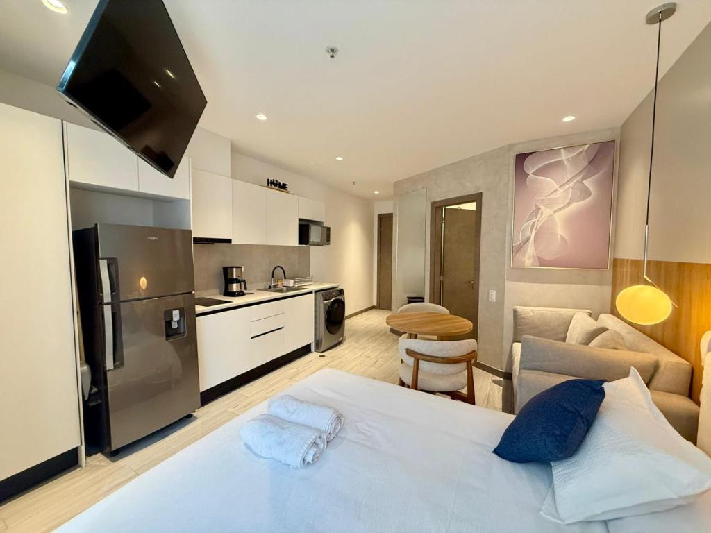 a bedroom with a white bed and a kitchen at Suite Ejecutiva de Lujo 2 personas, Wi-Fi, cafetera, GYM, Jacuzzy, a 3 minutos del Parque La Carolina in Quito