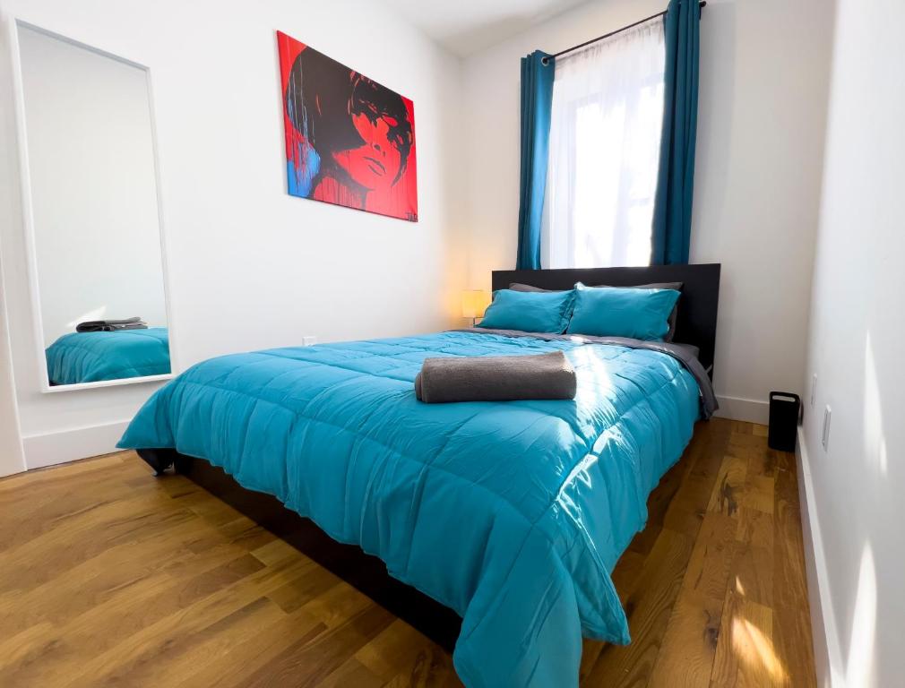 a bedroom with a bed with blue sheets and a window at The Chauncey Homestay in Brooklyn