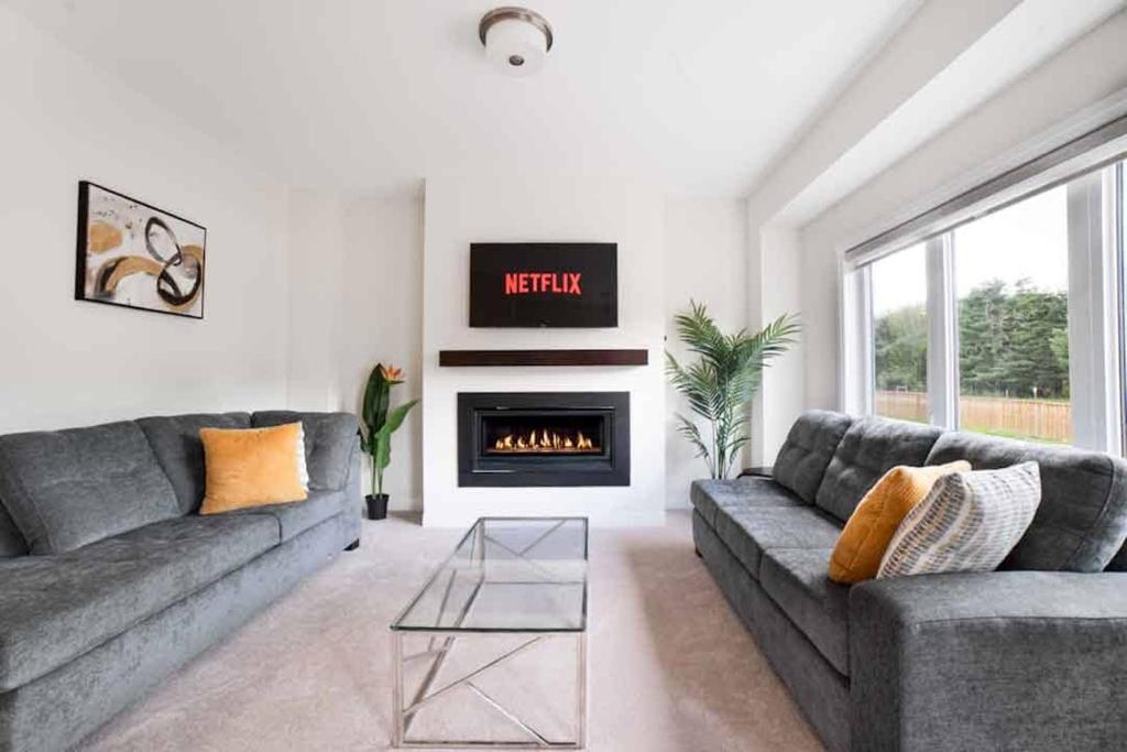 a living room with two couches and a fireplace at Tranquil Lakeside Townhouse in Severn
