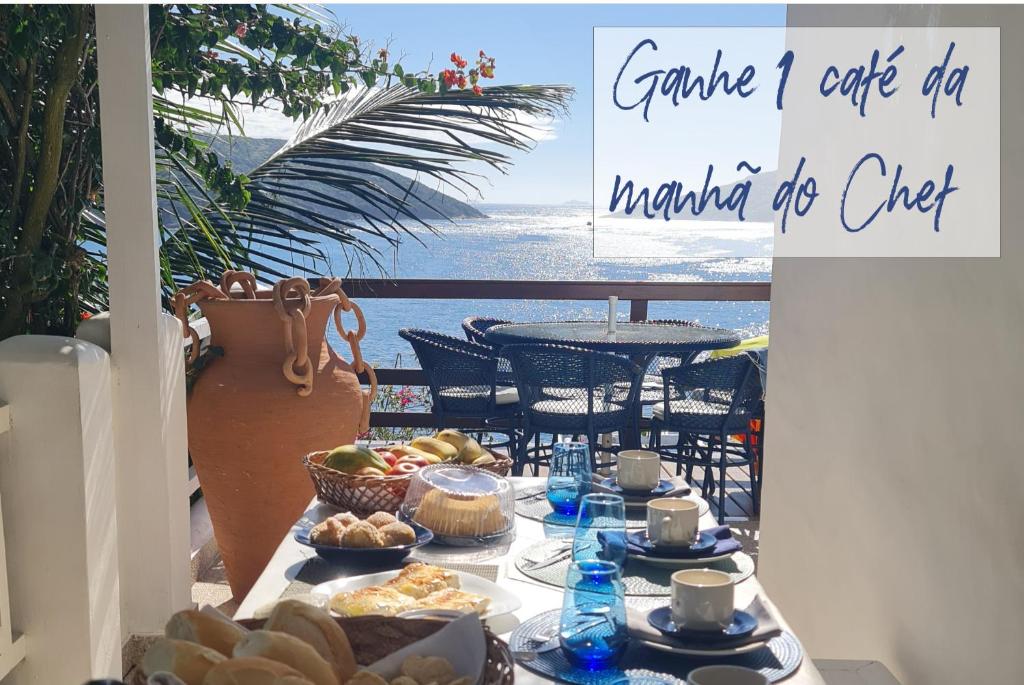 a table with food on it with a view of the ocean at Casa Mar da Grécia in Arraial do Cabo