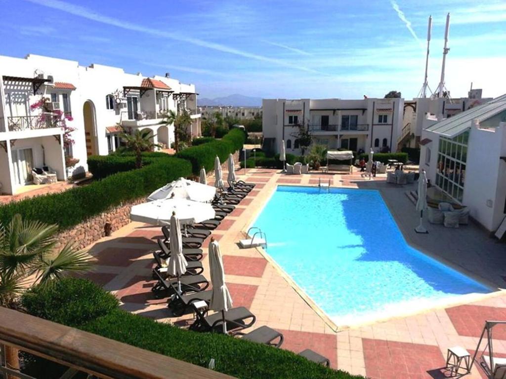 una piscina con sillas y sombrillas junto a algunos edificios en Logaina Sharm Resort Apartments, en Sharm El Sheikh