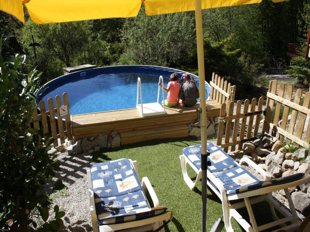 two people sitting under an umbrella next to a swimming pool at Holiday Home in Auvergne near Lake in Beaulieu