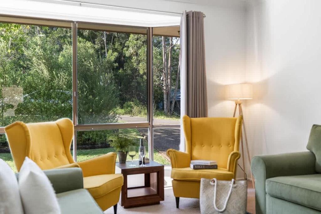 a living room with two yellow chairs and a window at Mollymook Memories - close to beach & golf course in Mollymook