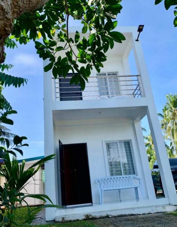 a white house with a balcony and a black door at Saraswati Exclusive Resort in Esperanza