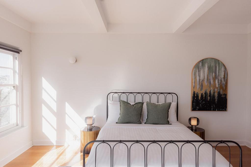 a white bedroom with a metal bed with green pillows at Light and Bright Trevallyn Stay with River Views in Royal Park