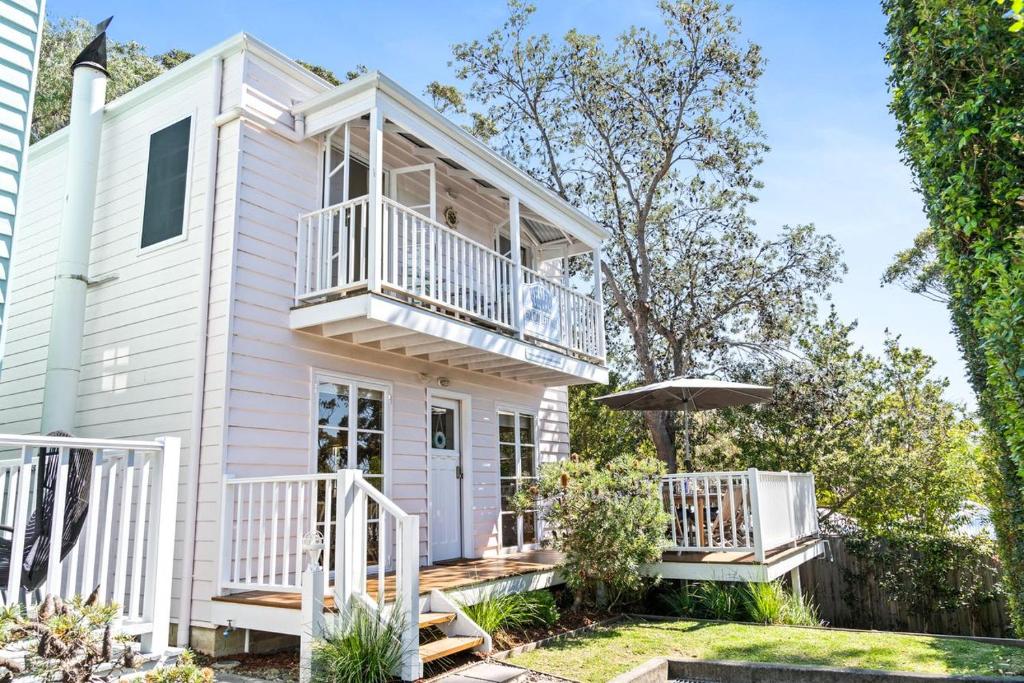 a white house with a porch and a balcony at Whalers Retreat - Hyams Beach 3BR cottage in Hyams Beach