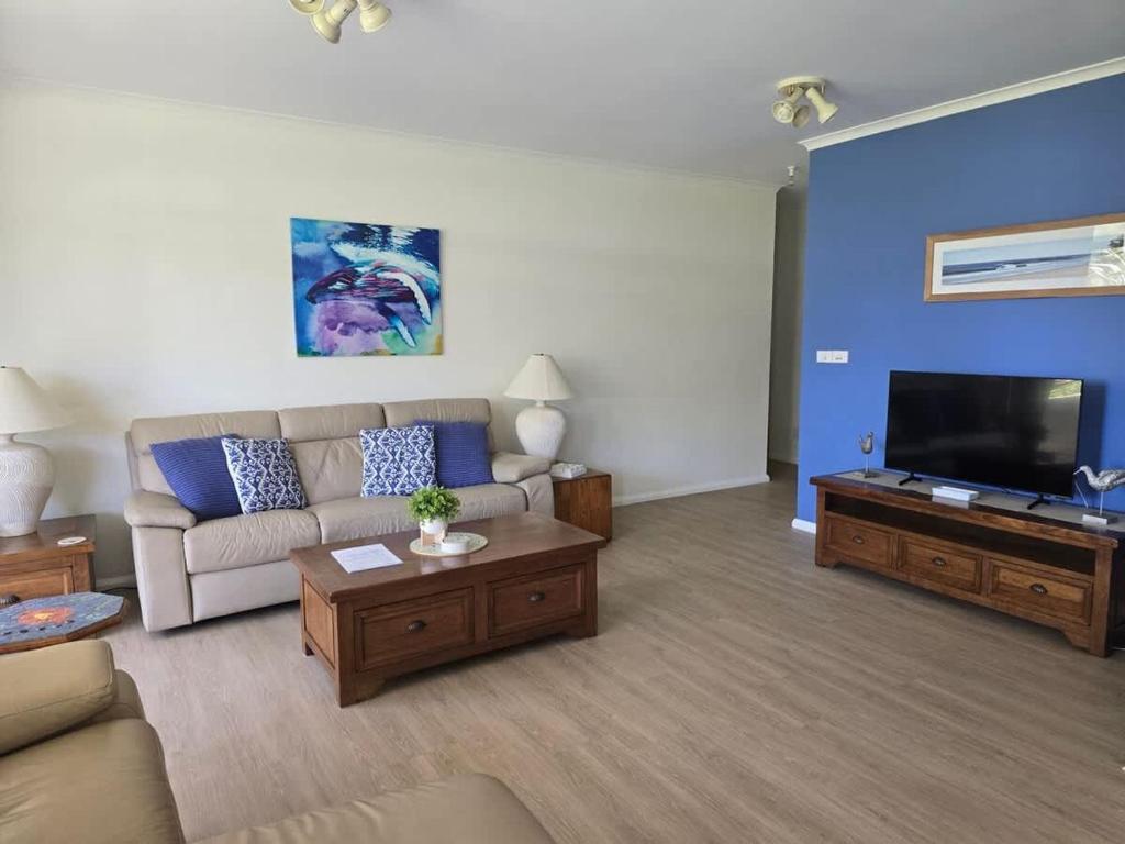 Una sala de estar con un sofá y un televisor de pantalla plana. en Fathoms 1 - 2BR beach resort apartment, en Mollymook