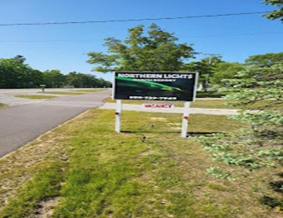 a sign in the grass next to a road at Northern Lights Beach Resort in Au Sable