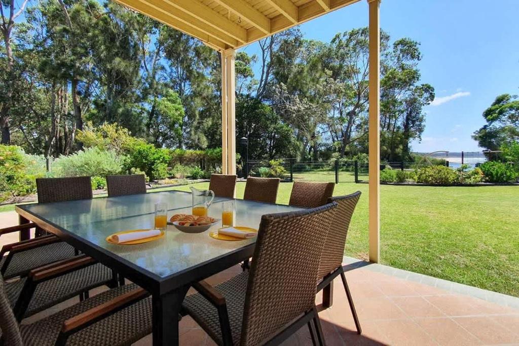 een eettafel op een patio met uitzicht op een veld bij Pelican Beach House - 50m from inlet & playground in Narrawallee