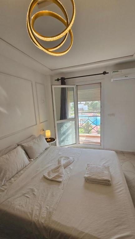 a bedroom with a large white bed with a chandelier at FamilyConfort Saidia in Saidia 