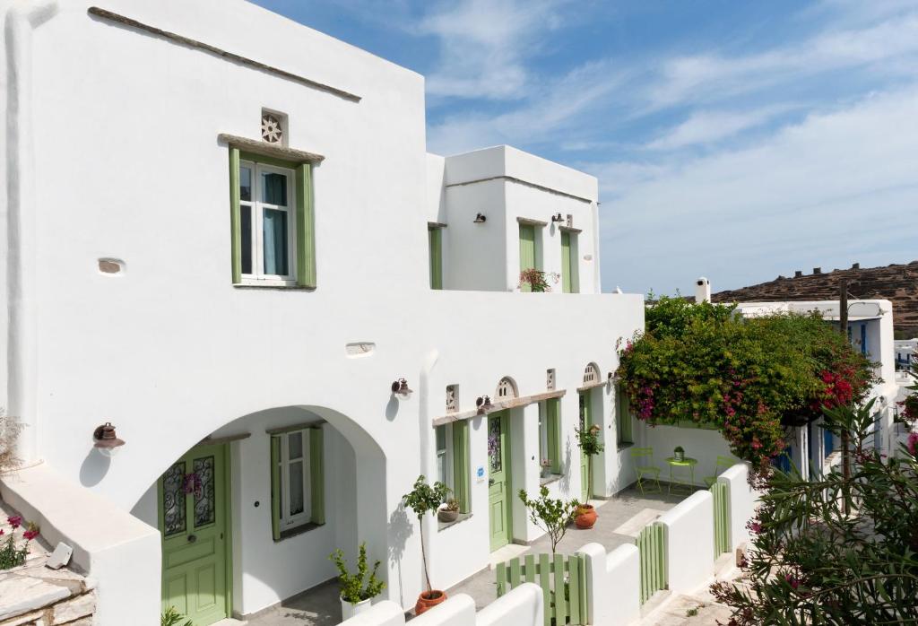 un edificio blanco con puertas y ventanas verdes en Skaris Guesthouse Tinos, en Pánormos