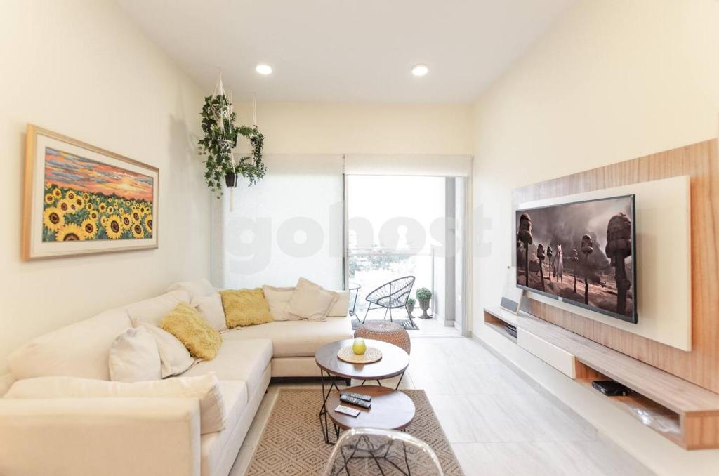 Una sala de estar con un sofá blanco y un televisor. en Spacious 2 Bedroom Apartment In Villa Morra, en Asunción