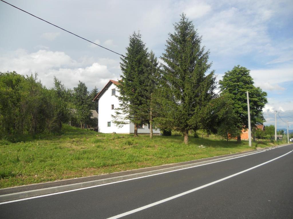 una casa blanca al lado de una carretera en Apartman Došen, en Ličko Petrovo Selo