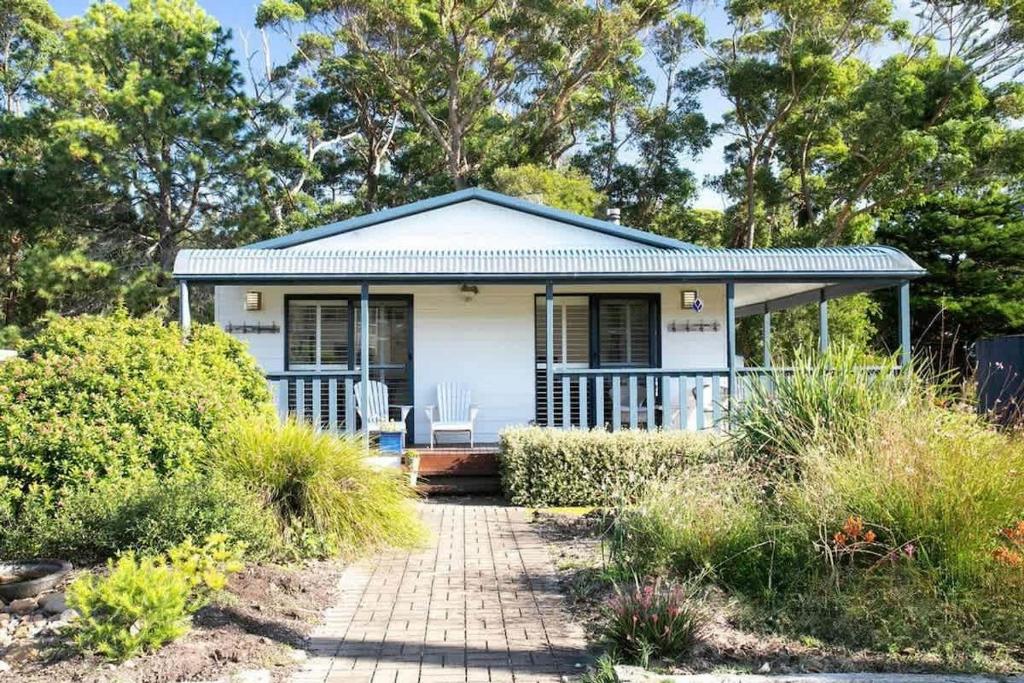 a small white house with a porch and a patio at Bawley Beach Bungalow in Bawley Point