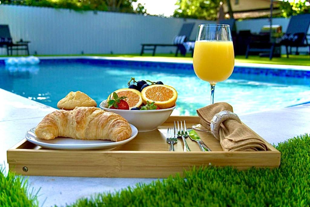 a tray with a plate of food and a glass of orange juice at CasaMia Only 10 min to Wynwood with New Pool, Bikes, Parking and Privacy in Miami