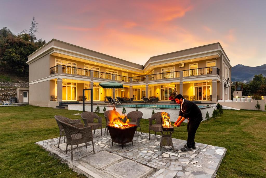 a man standing in front of a house with a fire pit at SaffronStays Sukh Saklana Haveli Royalty Rooms - Forest-view stay with pool, expansive lawns & dining near Rishikesh and Dehradun Airport in Dehradun