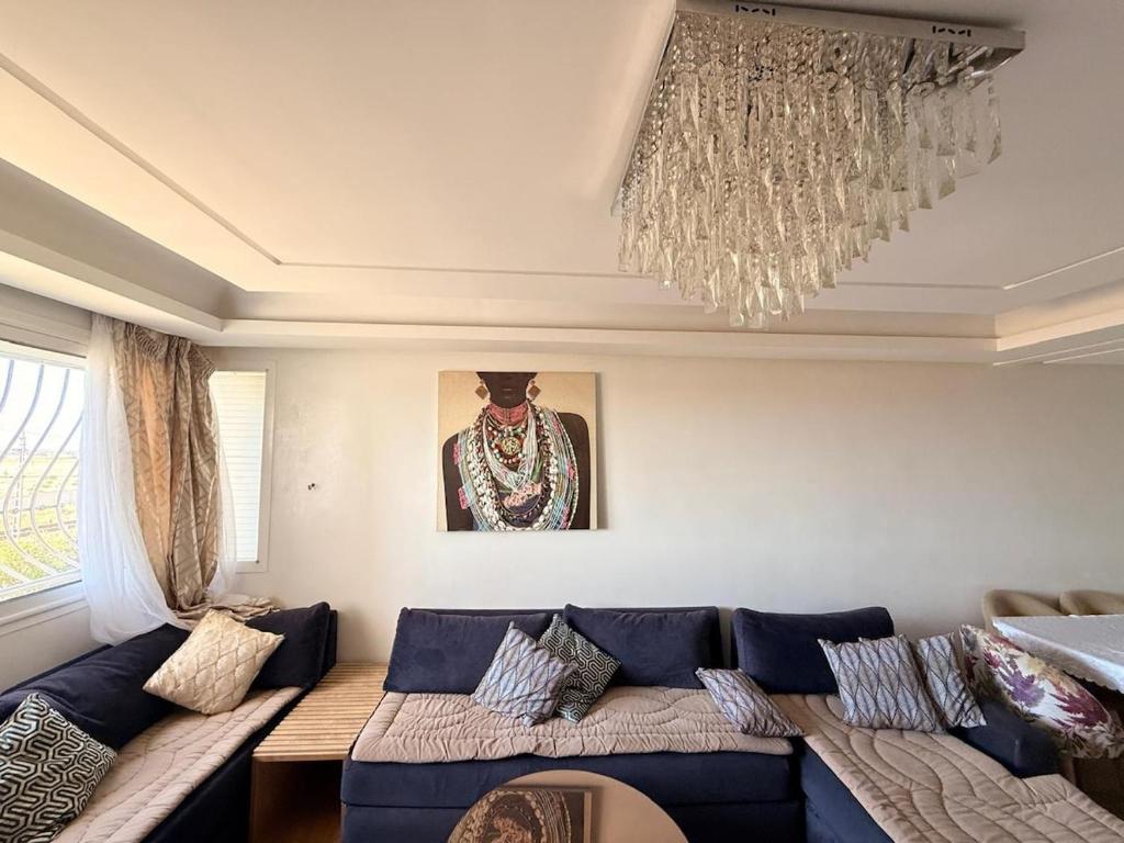 2P apartment, sea and pool في بوزنيقة: غرفة معيشة بها أريكة زرقاء وثريا