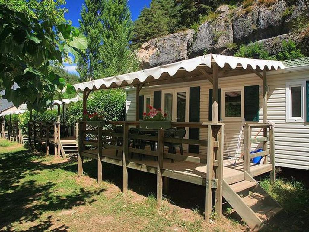 a small cabin with a porch and a wooden deck at Mobil home 6 pers avec terrasse - API-1-52-172 in Meyrueis